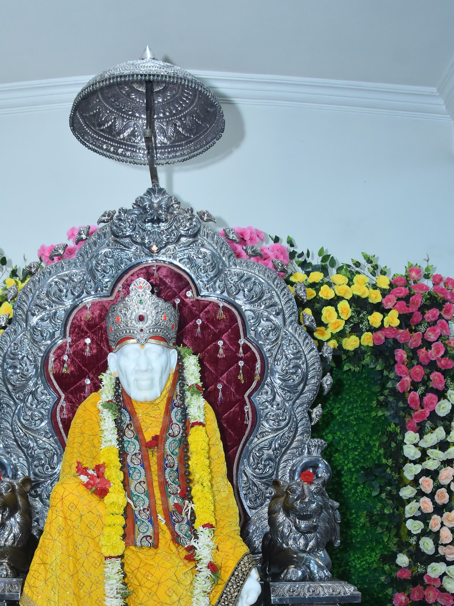 The murti draped in bright saffron cloth with a white garland.