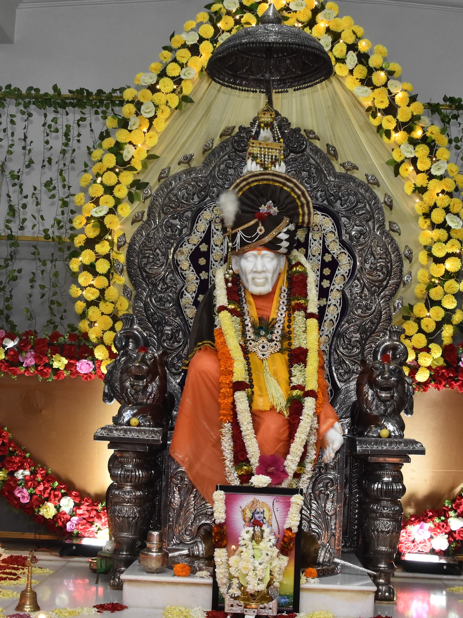 The murti in saffron and gold, heavily garlanded with marigolds.